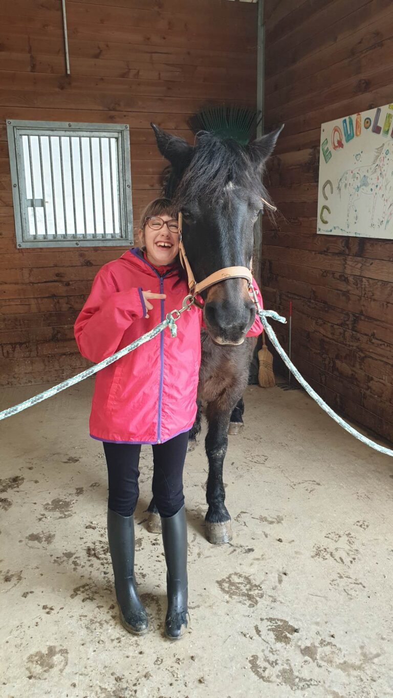 Photo de Angèle, jeune fille de 12 ans atteinte du syndrome CTNNB1. Elle est accompagnée d'un cheval.